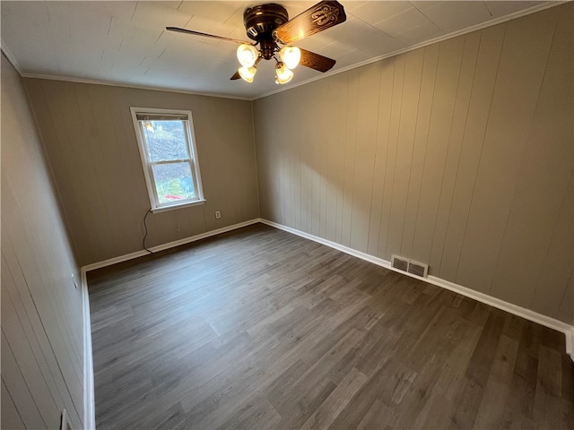 spare room with dark wood-type flooring, ceiling fan, and crown molding