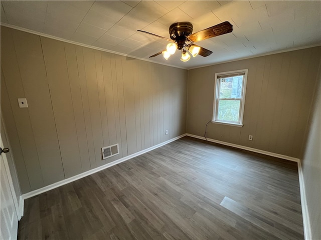 unfurnished room with crown molding, dark hardwood / wood-style floors, wooden walls, and ceiling fan