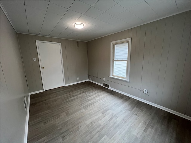 empty room featuring wooden walls and dark hardwood / wood-style floors