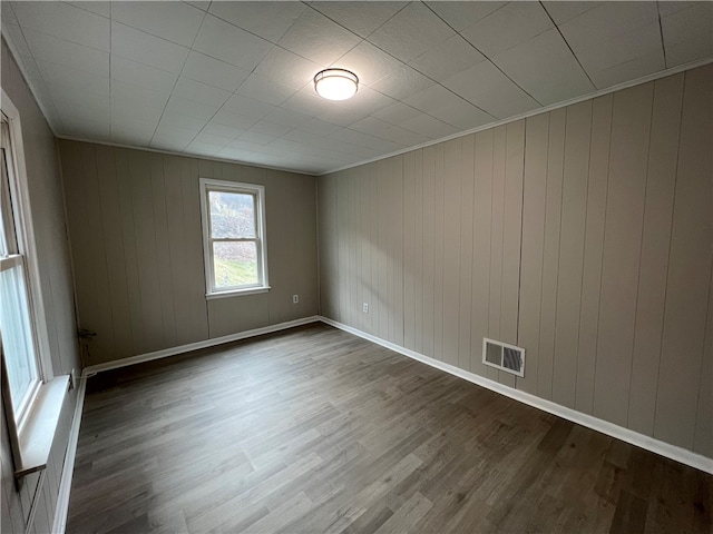 unfurnished room with wooden walls, crown molding, and hardwood / wood-style flooring