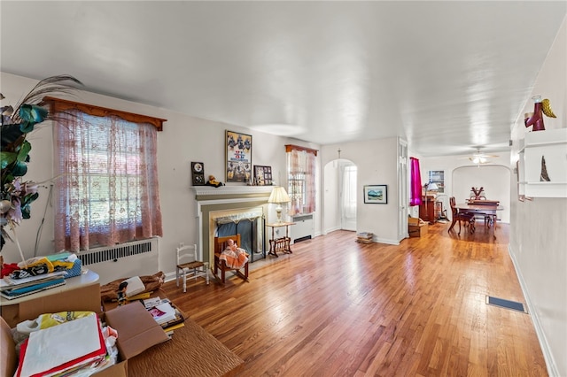 living room with ceiling fan, hardwood / wood-style flooring, radiator heating unit, and plenty of natural light