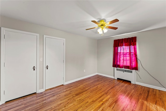 empty room featuring ceiling fan, wood-type flooring, and radiator