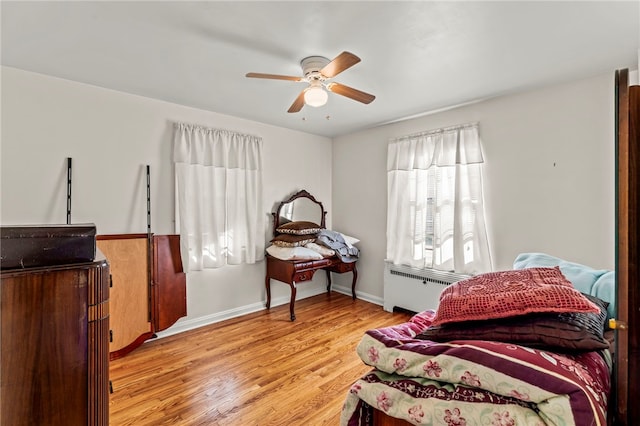 bedroom with ceiling fan, radiator heating unit, and light hardwood / wood-style floors