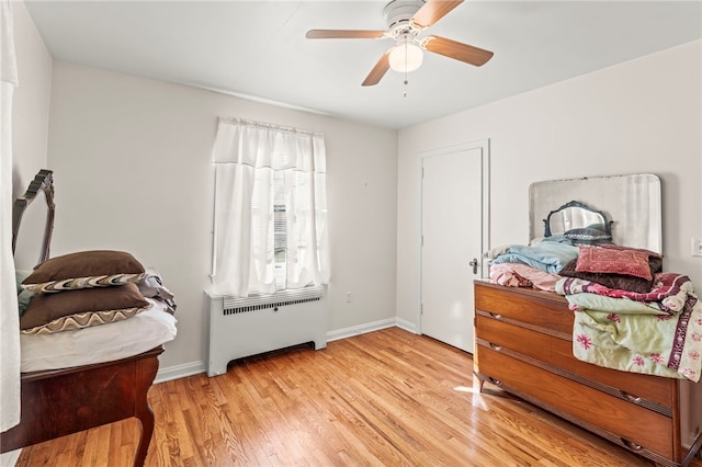 bedroom featuring radiator heating unit, light wood-type flooring, and ceiling fan