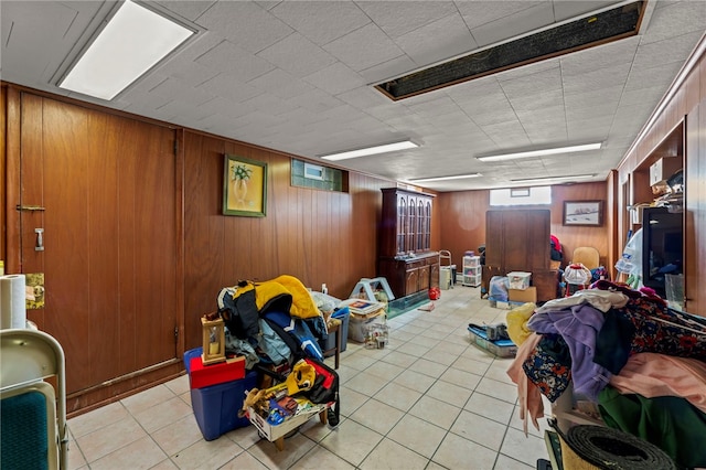 interior space with light tile patterned floors and wood walls