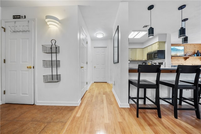 interior space featuring light hardwood / wood-style flooring, a kitchen bar, and green cabinets