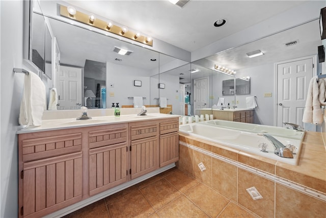 bathroom featuring vanity, a relaxing tiled tub, and tile patterned floors