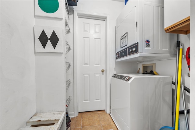 clothes washing area with light tile patterned flooring, stacked washer and clothes dryer, and cabinets