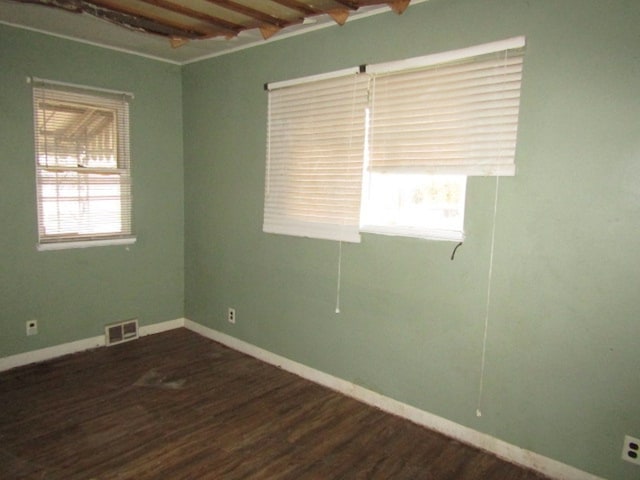 unfurnished room with dark hardwood / wood-style flooring, beamed ceiling, and a wealth of natural light