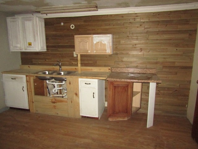 kitchen featuring wood walls, sink, white cabinets, ornamental molding, and dark hardwood / wood-style floors