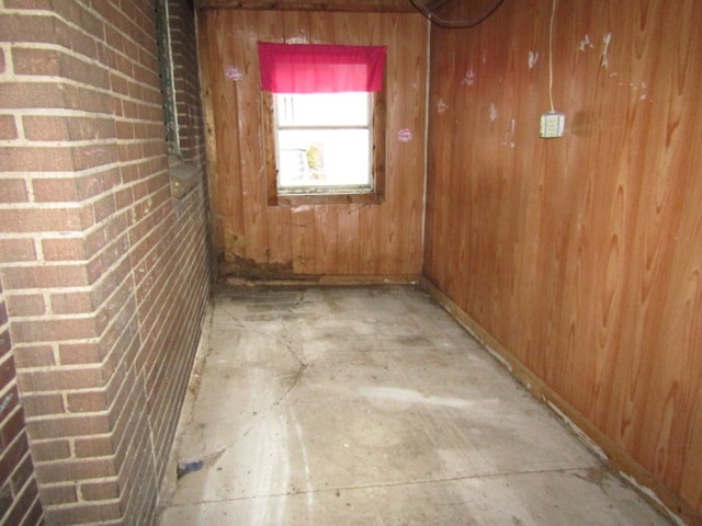 hall with brick wall, wooden walls, and concrete flooring