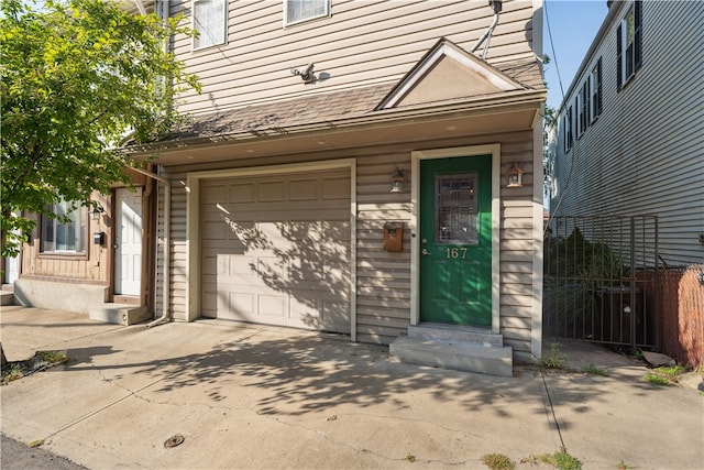 entrance to property with central AC, driveway, an attached garage, and fence