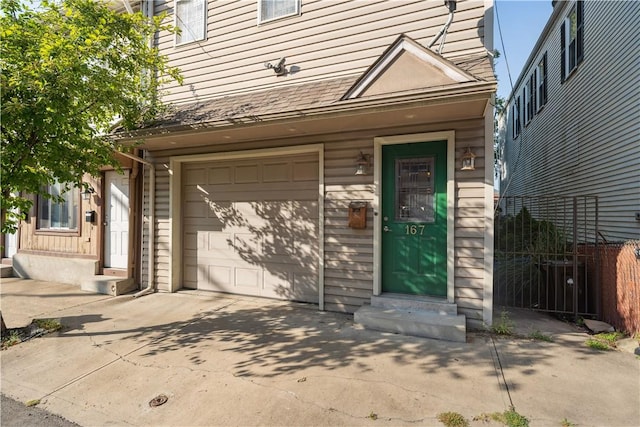 entrance to property with fence, an attached garage, and driveway