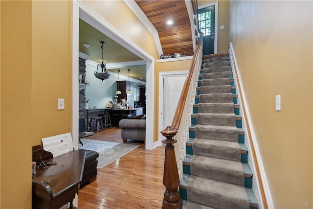 stairway with ornamental molding, recessed lighting, wood ceiling, and wood finished floors