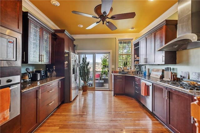 kitchen featuring crown molding, stainless steel appliances, light wood-style floors, ventilation hood, and dark stone counters