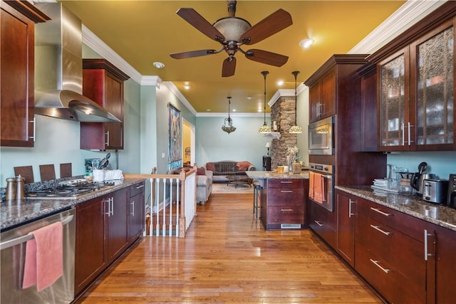 kitchen with glass insert cabinets, a kitchen breakfast bar, decorative light fixtures, extractor fan, and stainless steel appliances