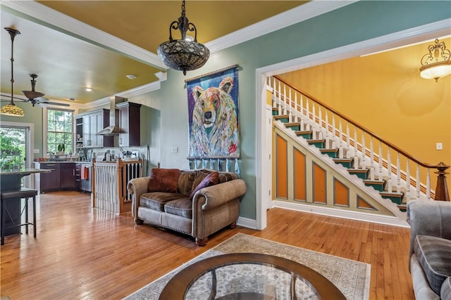 living area with stairs, ornamental molding, and wood finished floors