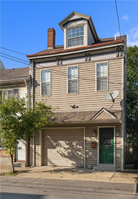 view of front facade with an attached garage and a chimney
