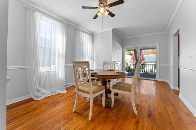 dining area featuring ornamental molding, a textured ceiling, light wood-type flooring, and ceiling fan