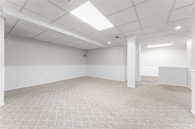 basement with a paneled ceiling and light colored carpet