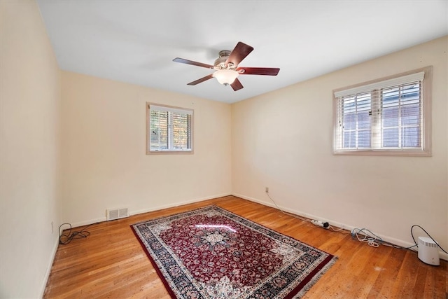 empty room with ceiling fan, hardwood / wood-style floors, and a healthy amount of sunlight