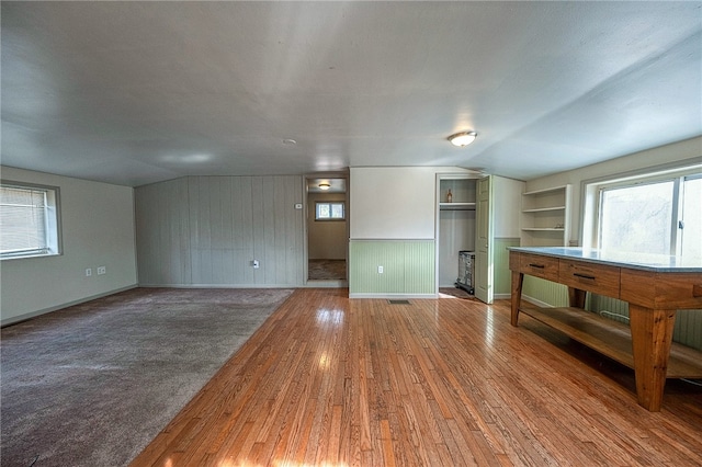 unfurnished living room featuring built in shelves, lofted ceiling, and hardwood / wood-style flooring