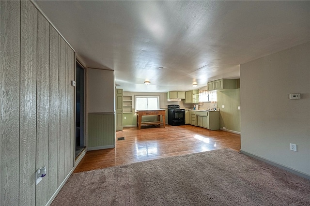 kitchen featuring black / electric stove, wooden walls, and light hardwood / wood-style flooring