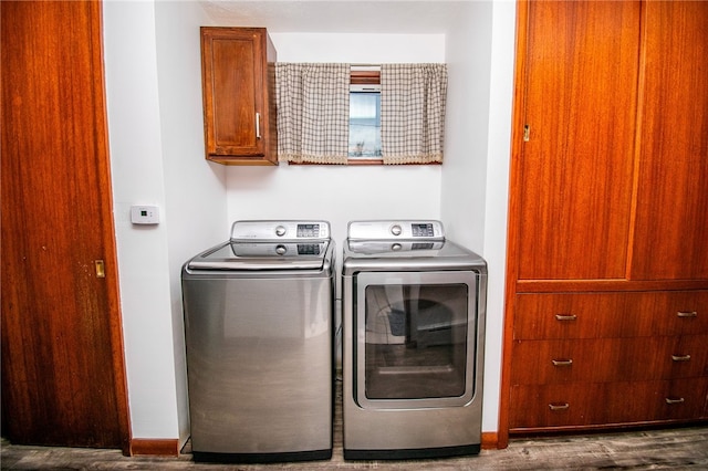 clothes washing area with cabinets, hardwood / wood-style floors, and washer and clothes dryer