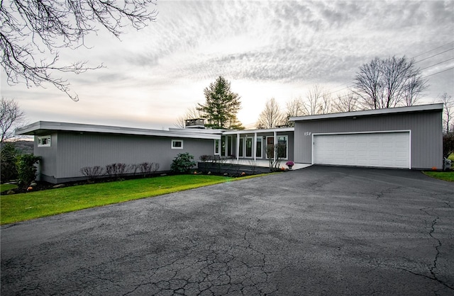 single story home featuring a sunroom, a garage, and a front yard