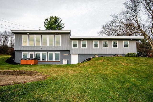 rear view of property with a yard and a hot tub