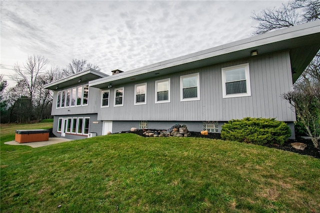 rear view of house featuring a patio, a yard, and a hot tub