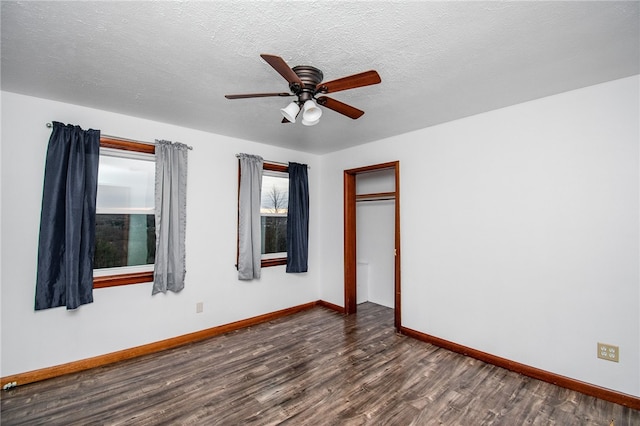 empty room with a textured ceiling, ceiling fan, and dark hardwood / wood-style floors