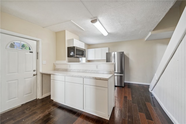 kitchen with white cabinets, a textured ceiling, dark hardwood / wood-style flooring, and stainless steel appliances