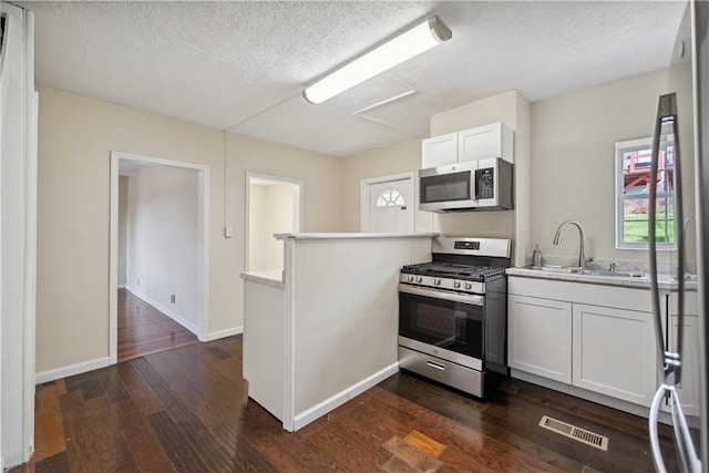 kitchen featuring dark hardwood / wood-style floors, kitchen peninsula, a textured ceiling, white cabinets, and appliances with stainless steel finishes