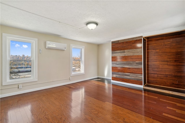 unfurnished room featuring wood-type flooring, a textured ceiling, and a wall unit AC