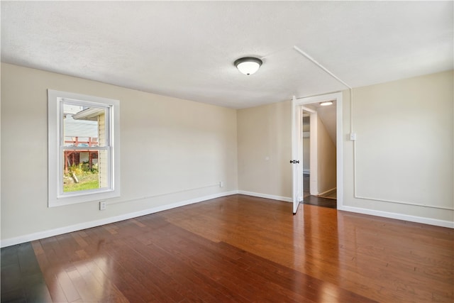 spare room with a textured ceiling and dark hardwood / wood-style floors