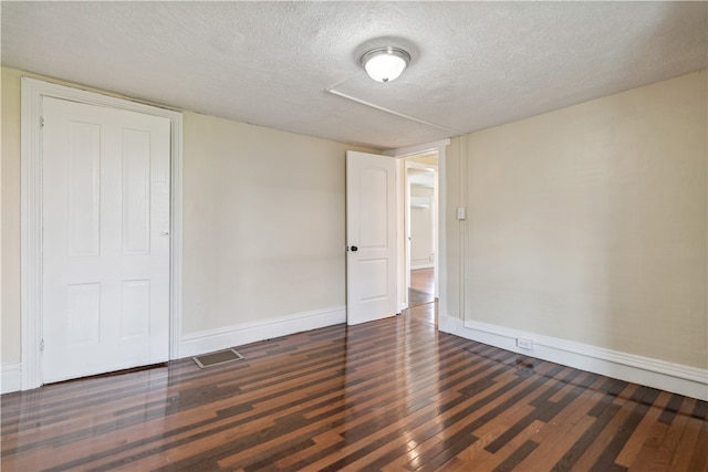 empty room featuring dark hardwood / wood-style flooring and a textured ceiling