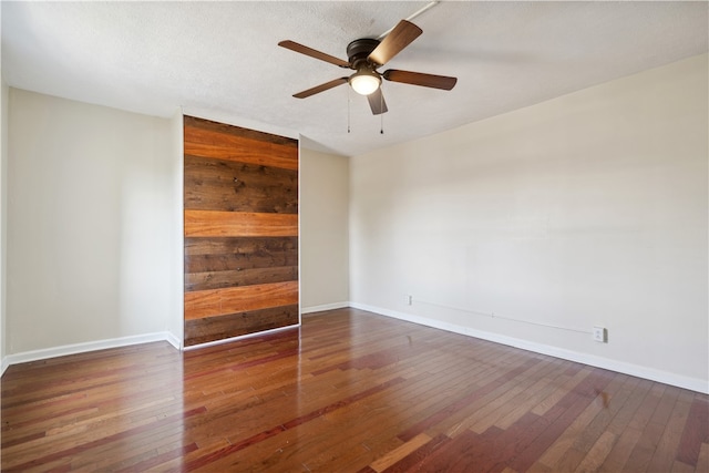 spare room featuring wood walls, dark hardwood / wood-style flooring, and ceiling fan