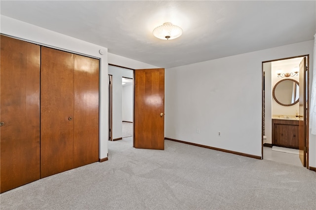 unfurnished bedroom with light carpet, a closet, and ensuite bath