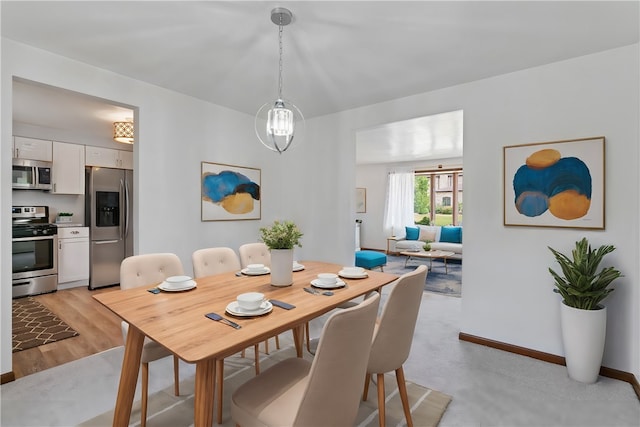 dining area with light hardwood / wood-style flooring and an inviting chandelier