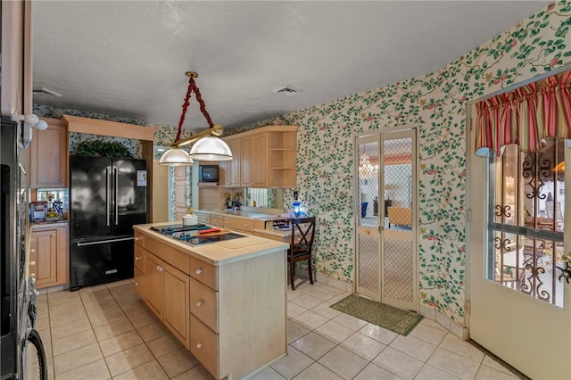 kitchen with light brown cabinetry, black appliances, pendant lighting, and light tile patterned floors