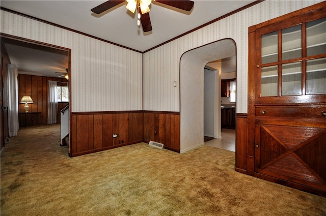 carpeted spare room featuring crown molding and wooden walls