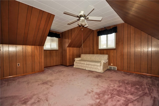 bonus room featuring wooden walls, vaulted ceiling, light colored carpet, and ceiling fan