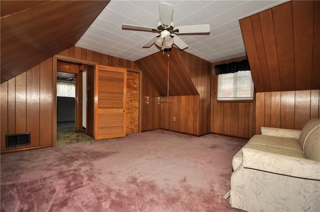 bonus room with a wealth of natural light, wooden walls, and ceiling fan