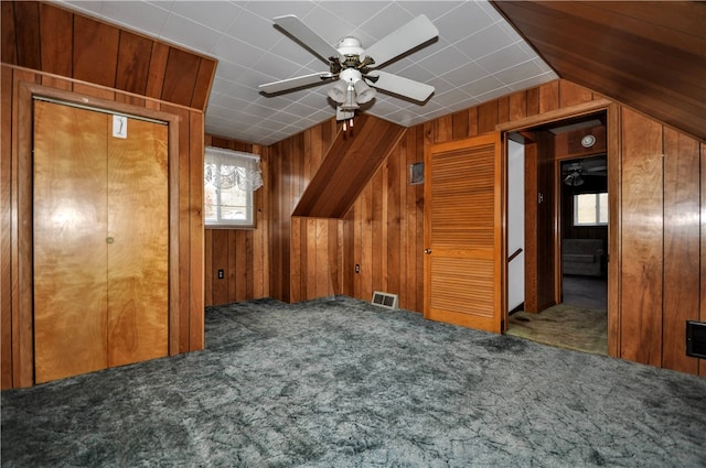 bonus room featuring wooden walls, vaulted ceiling, carpet flooring, and ceiling fan