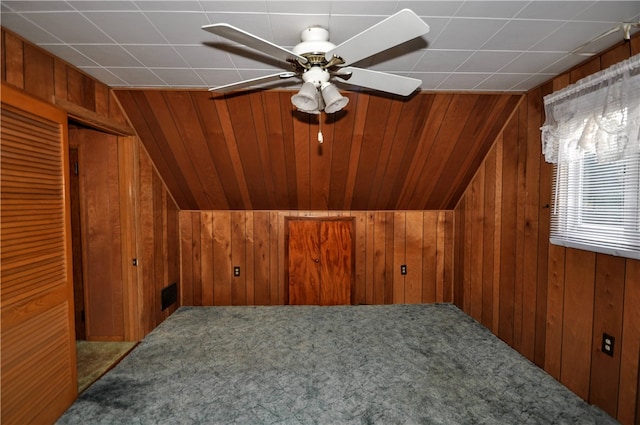 additional living space with lofted ceiling, wood walls, carpet flooring, and ceiling fan