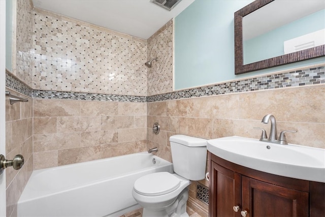 full bathroom with tile walls, vanity, tiled shower / bath, and toilet