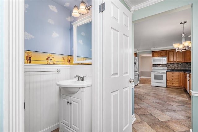 bathroom with vanity, crown molding, a notable chandelier, and tasteful backsplash