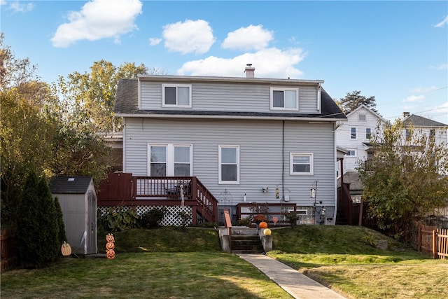 back of house featuring a lawn, a wooden deck, and a storage shed