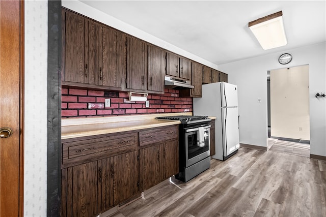 kitchen with dark brown cabinetry, tasteful backsplash, stainless steel stove, white fridge, and light hardwood / wood-style flooring